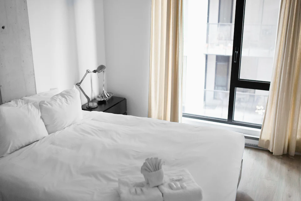 Camera da letto luminosa con letto bianco accanto alla finestra