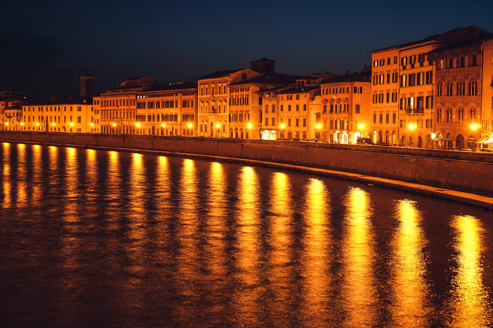 I palazzi del Lungarno di Pisa illuminati di sera e riflessi nel fiume